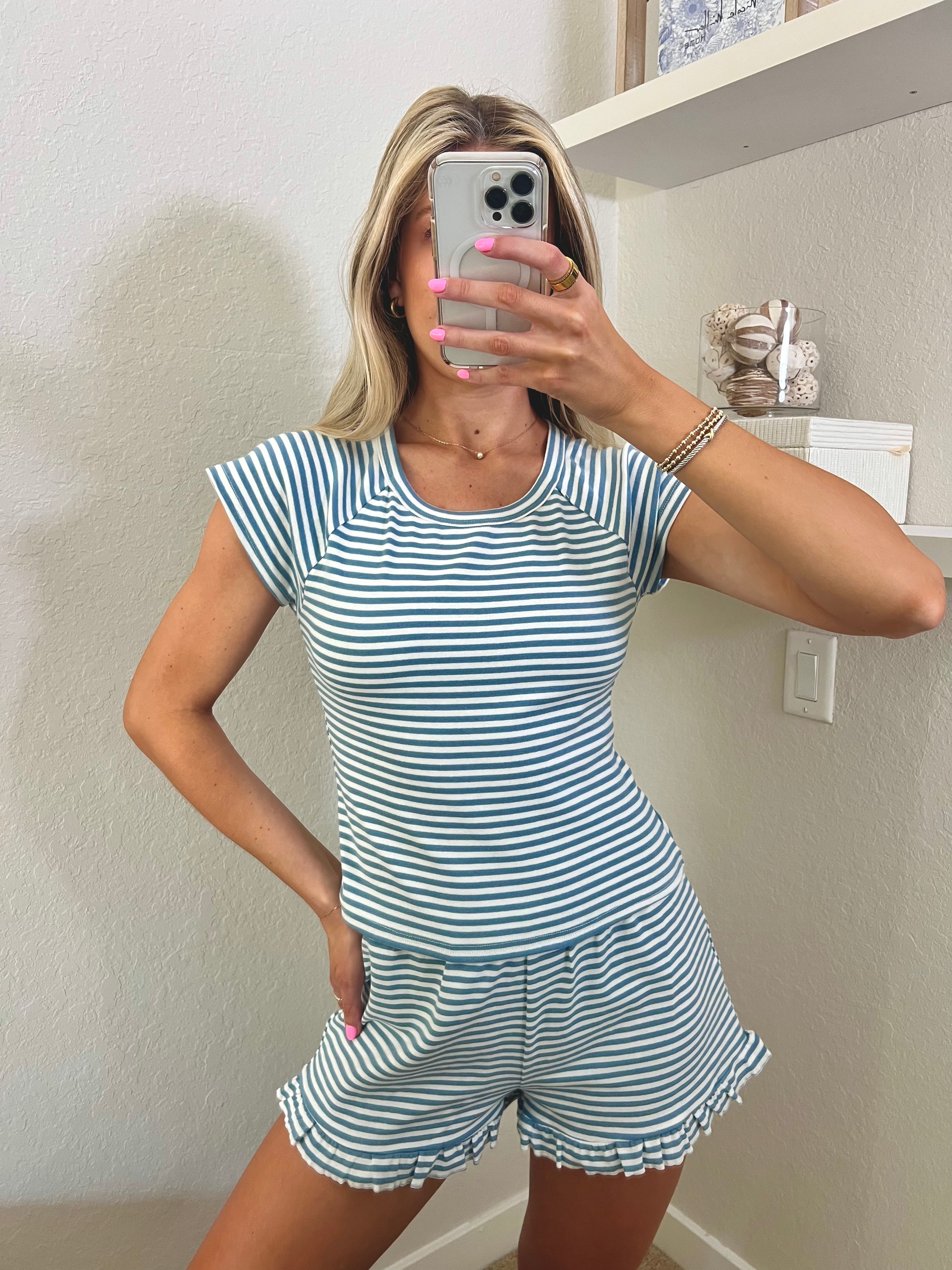 Woman taking a mirror selfie wearing a blue and white striped set in a room.