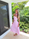 Woman in a pink and white striped maxi skirt set with a scarf standing outdoors with greenery in the background