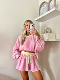 Woman wearing a pink and white striped long sleeve and shorts set with yellow trim taking a mirror selfie.