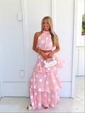 Woman wearing a pink polka dot skirt set holding a white clutch on a bright white patio.