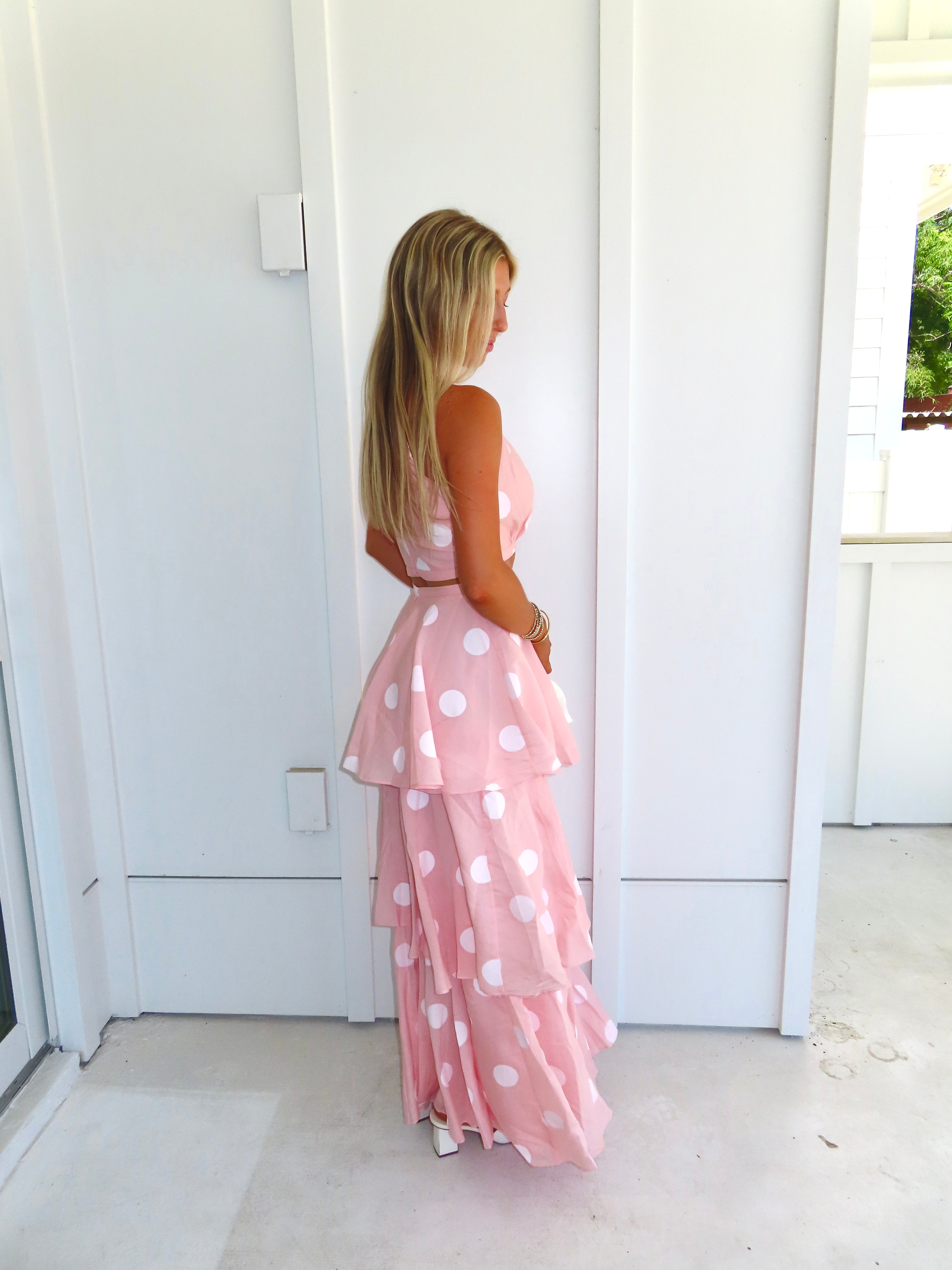 Woman wearing a pink polka dot skirt set on a bright white patio.