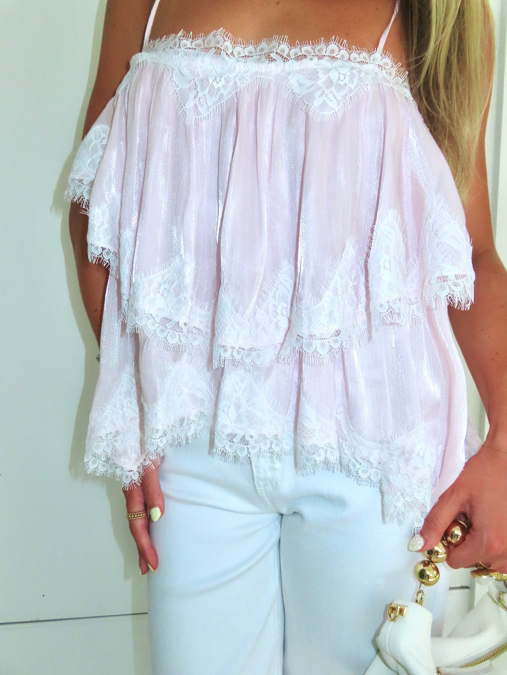 Light pink lace top worn by a person against a plain background