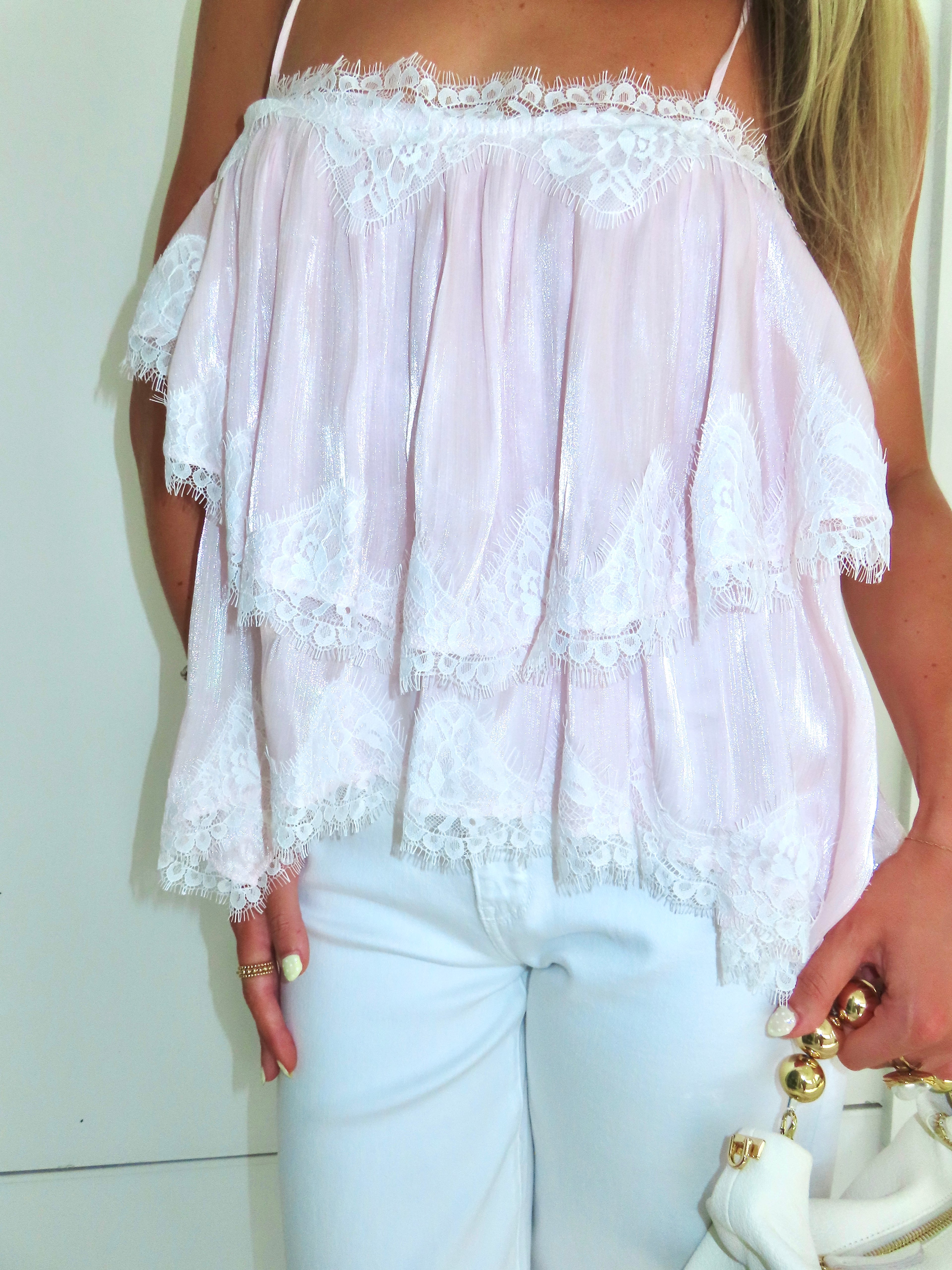 Light pink lace top worn by a person against a plain background