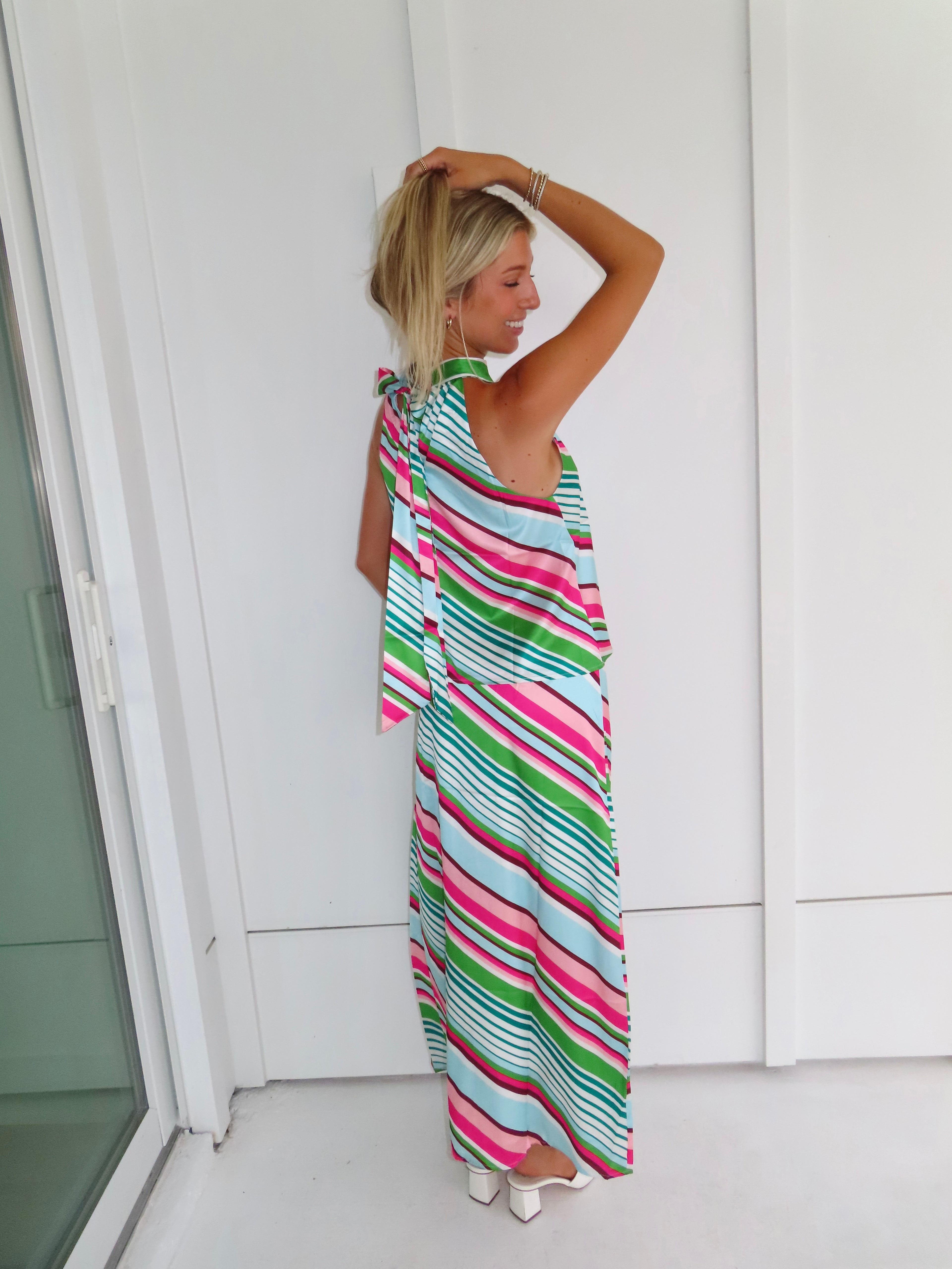 Woman wearing a colorful striped maxi skirt set standing in front of a white wall.