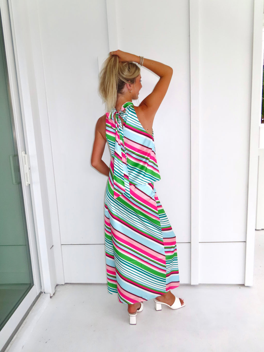 Woman wearing a colorful striped maxi skirt set standing in front of a white wall.
