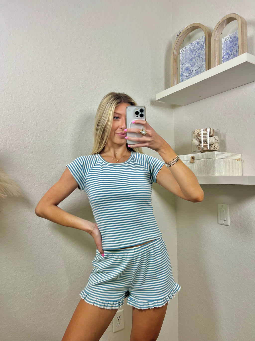 Woman taking a mirror selfie wearing a blue and white striped lounge set.