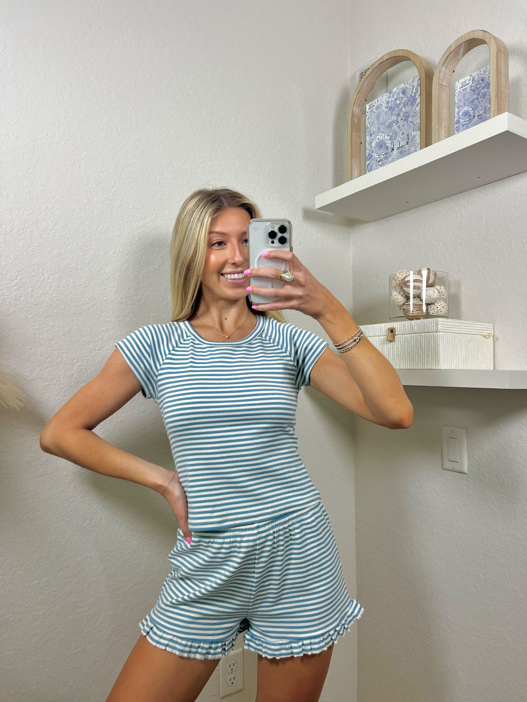 Woman taking a mirror selfie wearing a blue and white striped lounge set.