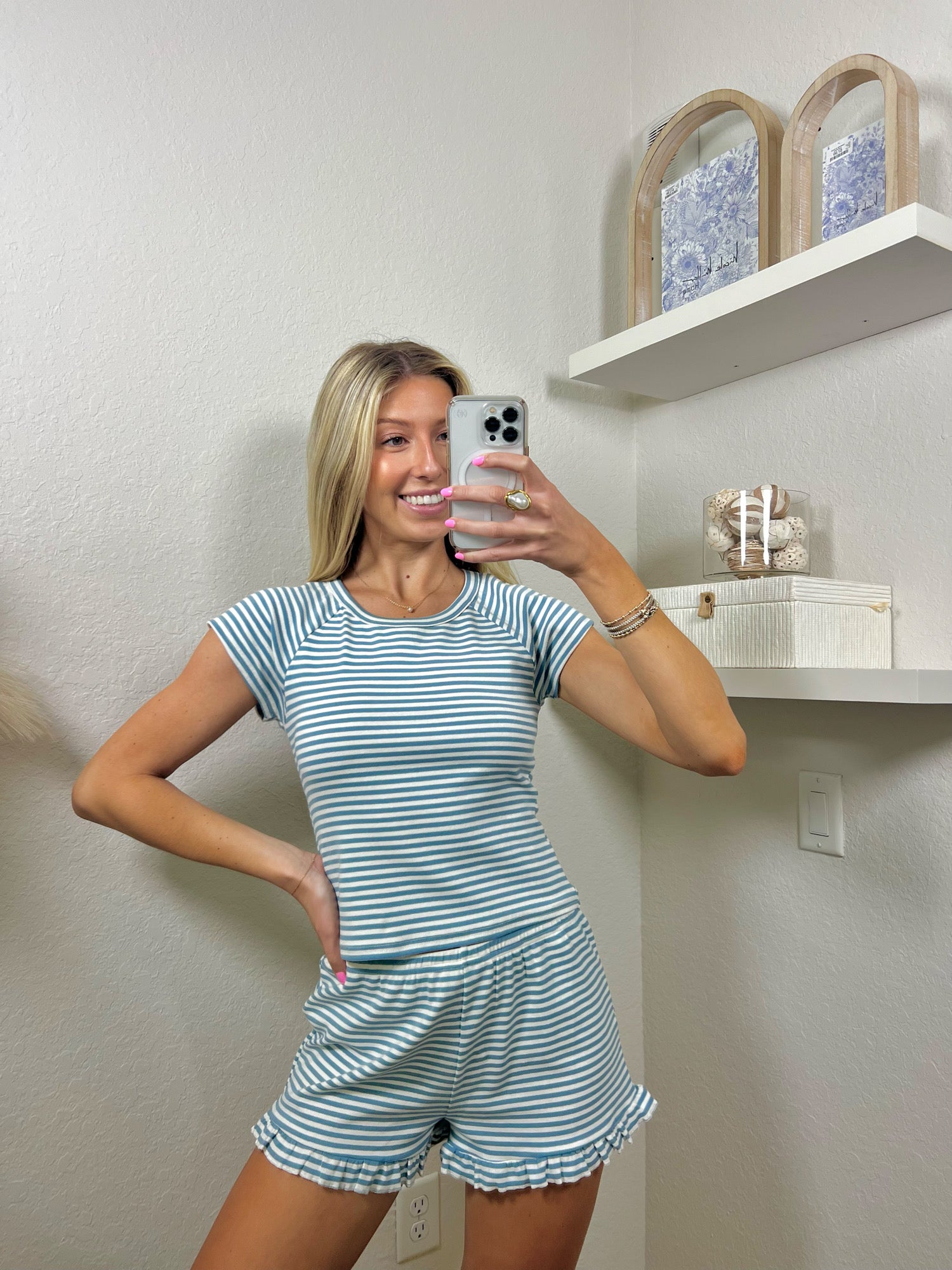 Woman taking a mirror selfie wearing a blue and white striped lounge set.