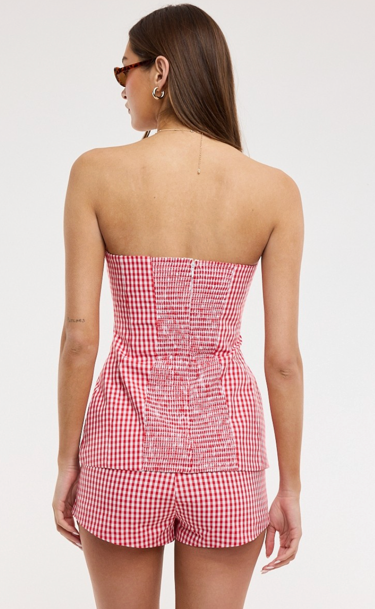 Woman wearing a red and white checkered strapless romper on a white background
