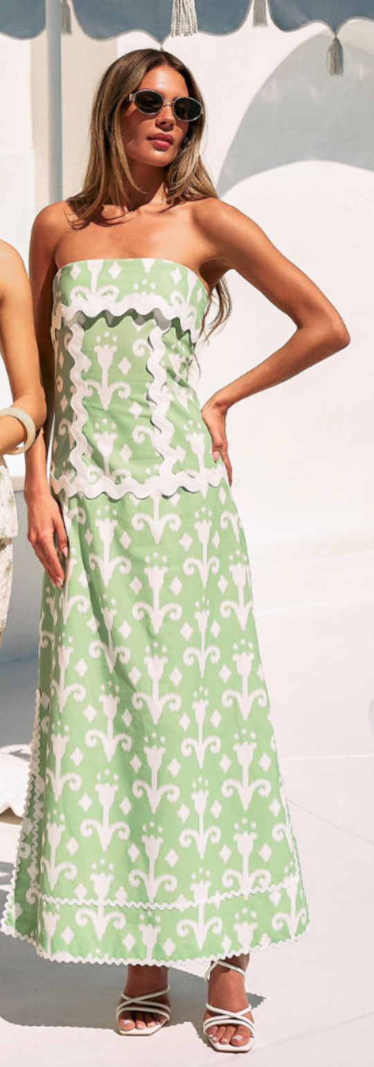 Woman wearing a strapless green dress with white floral pattern outdoors.
