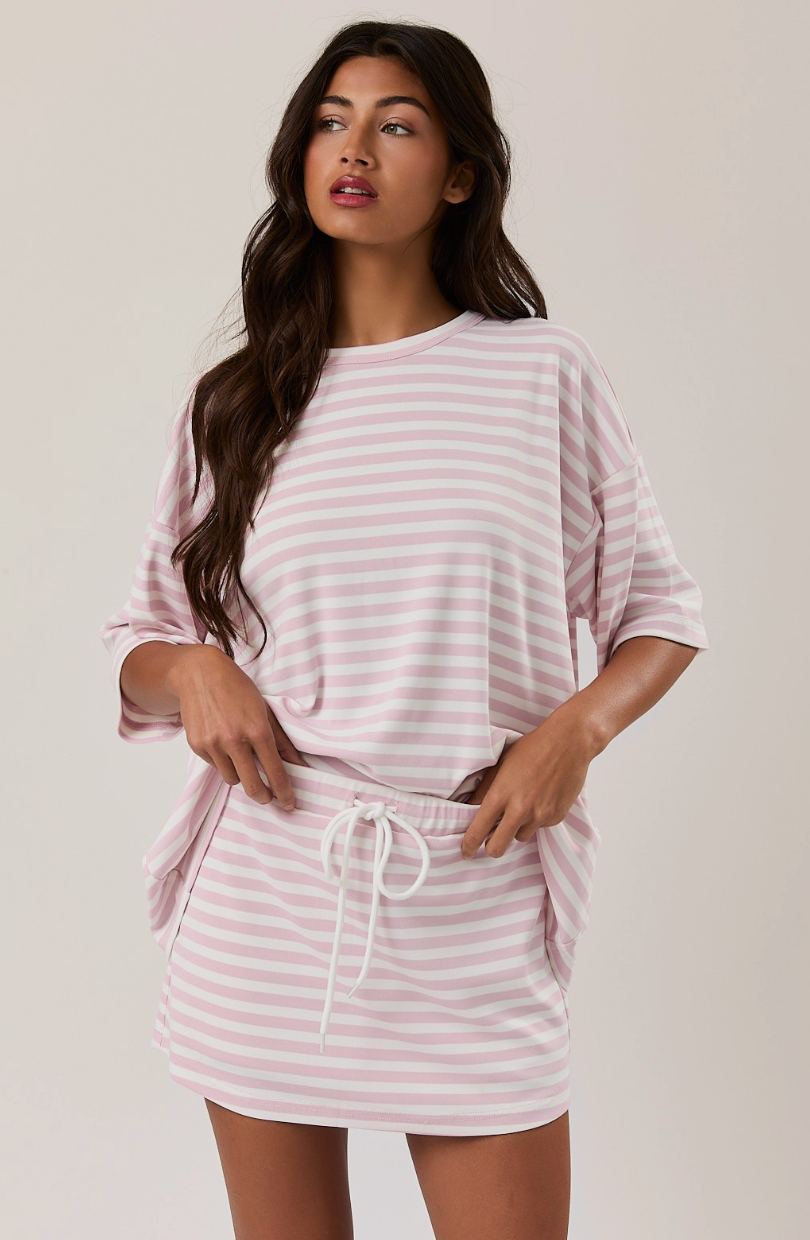Woman wearing a pink and white striped skort set on a plain background