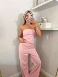 Woman taking a mirror selfie wearing a pink and ivory striped tube top and pants set in a room.